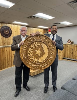 Current 422nd District Court Judge Shelton Gibbs (at right) presented a custom, handmade wooden county seal that hung in the 422nd District Court for decades to former District Court Judge Mike Chitty during the Jan. 3 meeting of the Kaufman County Commissioners Court. Courtesy photo