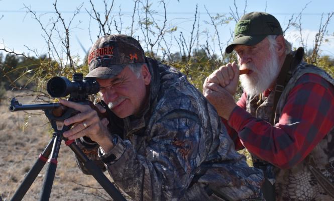 Jeff Rice (left) takes aim at a distant coyote that Larry Weishuhn is calling with his mouth predator call. Photo by Luke Clayton