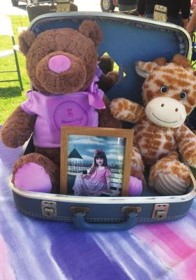 A pair of stuffed animals with a photograph of Alana at a recent donation event. COURTESY PHOTO