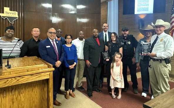 Pastor Billy Gardner of the Cross County Ministers Coalition (center) presented a plaque to Devon Candanoza, wife of slain Terrell Police officer Jacob Candanoza, who was killed in the line of duty Dec. 8, 2024. Another plaque in memory of Officer Candanoza was presented to Terrell Police Chief Arley Sansom. The presentations were made at the April 22 Terrell City Council meeting. See related photos on 7A. Photo courtesy of City of Terrell Facebook page
